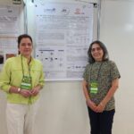 Pesquisadoras diante do pôster sobre proteínas das amêndoas de bocaiuva e seu potencial bioativo, no SLACAN 2025.