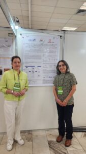 Pesquisadoras diante do pôster sobre proteínas das amêndoas de bocaiuva e seu potencial bioativo, no SLACAN 2025.