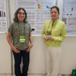 Lígia Macedo e Ana Cristina Jacobowski diante do pôster sobre atividade antimicrobiana de um peptídeo bioinspirado, no SLACAN 2025.