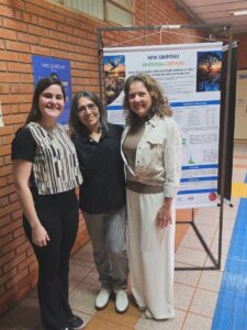 Pesquisadoras diante do pôster sobre a ação seletiva do peptídeo Acro-18 em células de melanoma.