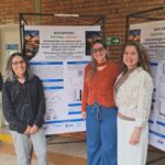 Pesquisadoras diante do pôster sobre nanopartículas de quitosana contendo extrato da casca de baru.