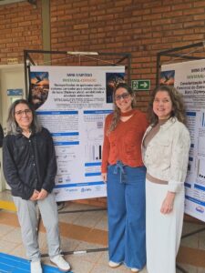 Pesquisadoras diante do pôster sobre nanopartículas de quitosana contendo extrato da casca de baru.