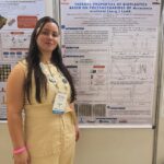 Larissa Lorrayne Alves da Silva diante do pôster sobre as propriedades térmicas de bioplásticos de bocaiuva.