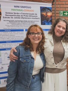 Maria Beatriz Pereira e Ana Cristina diante do pôster sobre síntese verde de nanopartículas de prata utilizando extrato de jatobá.