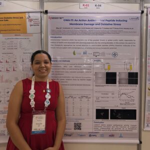 Vitória Silva diante do pôster sobre a atividade antimicrobiana do peptídeo GWA-17.